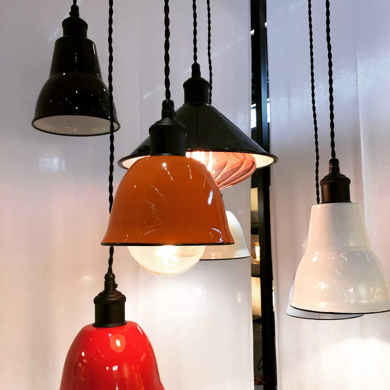 Les lampes suspendues exposées sont de couleur rouge, orange, blanche et noire.